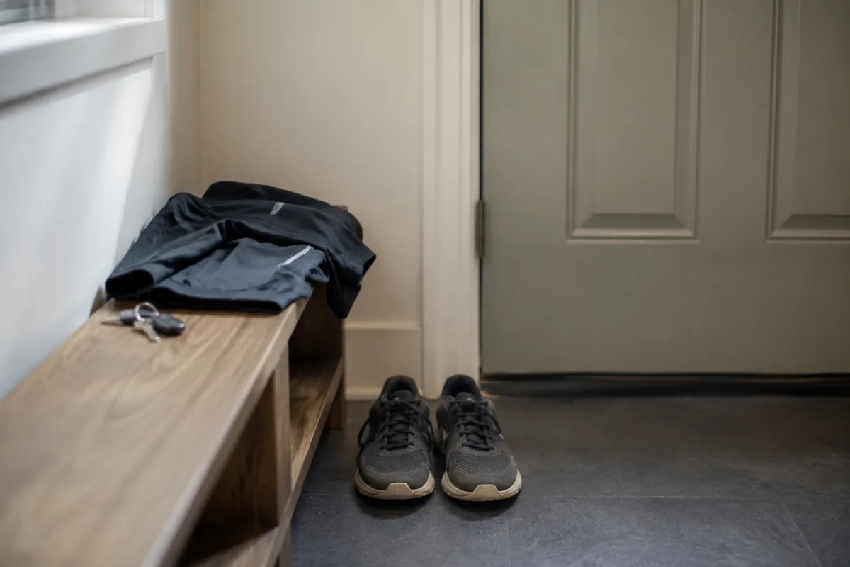 Buty biegowe stoją przy drzwiach wejściowych w przedpokoju, obok złożona bluza